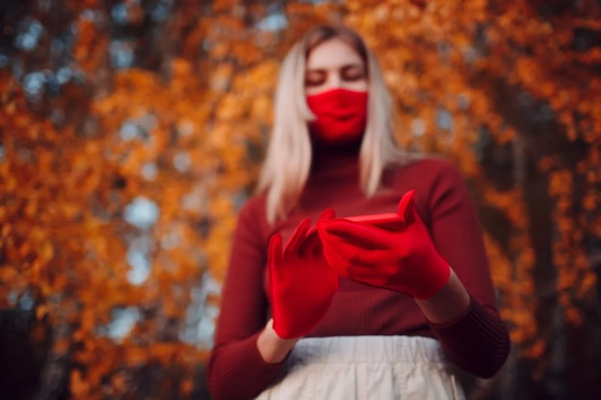 person using smartphone in autumn park gloves