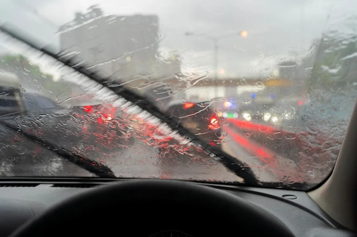 car driving in heavy rain seen through windshield navigation display