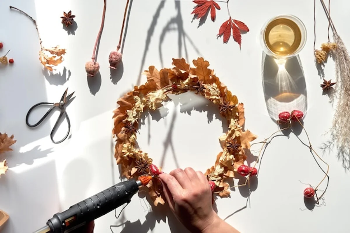 making autumn wreath with chestnuts cones berries hands