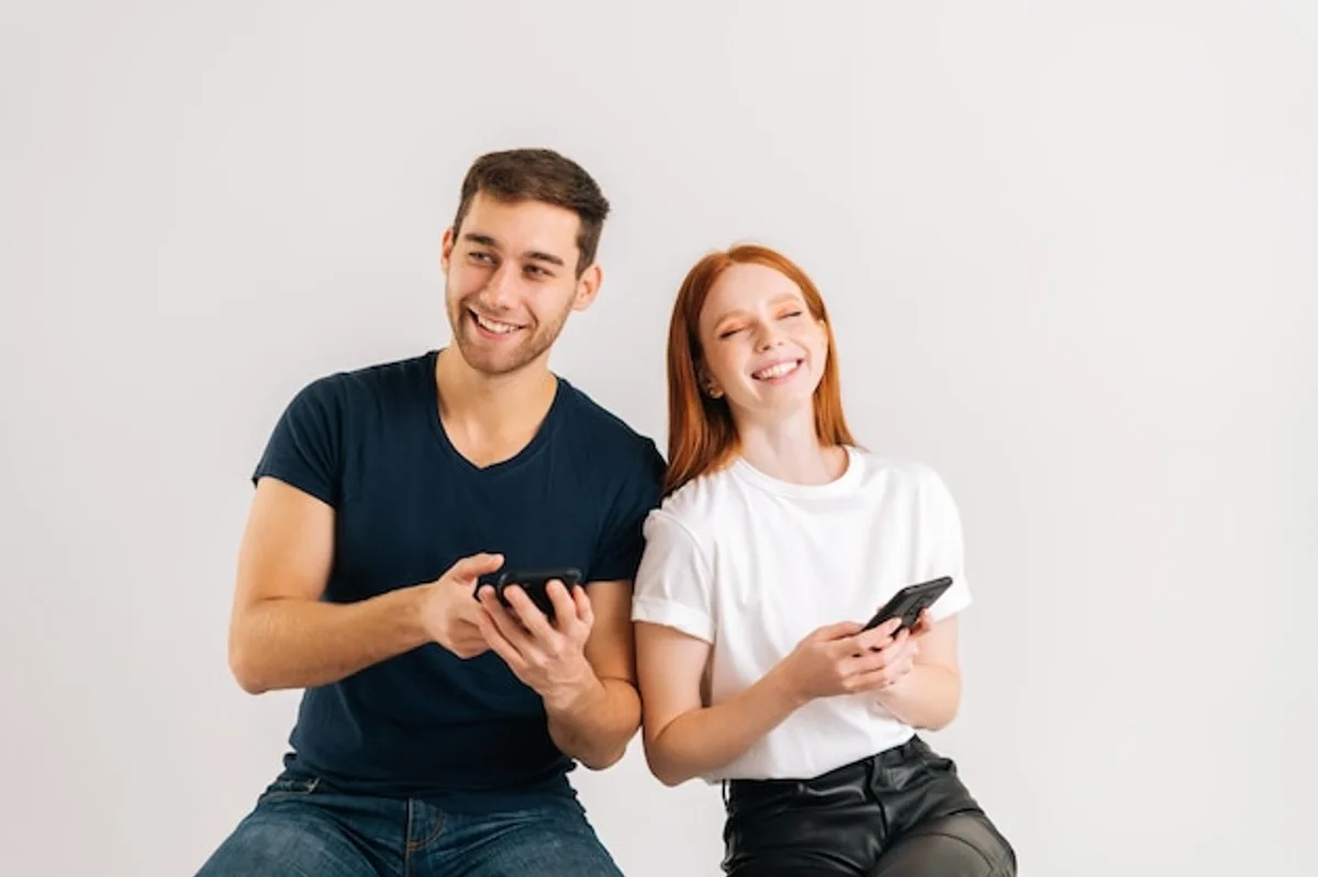 couple laughing while texting on smartphone, friendly communication