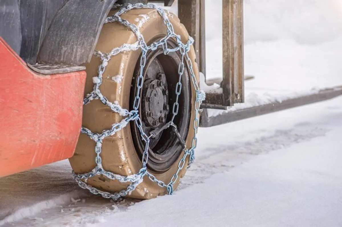 man putting snow chains on car wheel in snowstorm