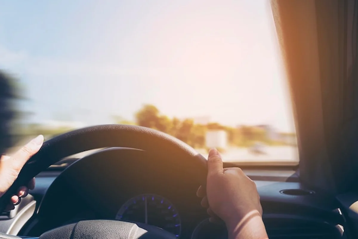 driver relaxing hand on steering wheel sun glare car interior